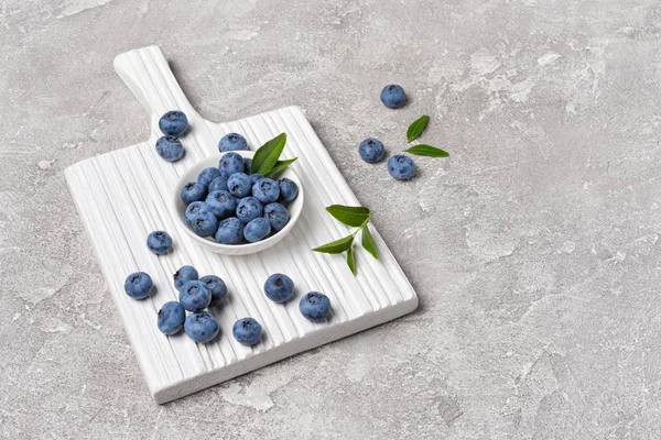 Färska blåbär bär i vit skål på trä kartong — Stockfoto