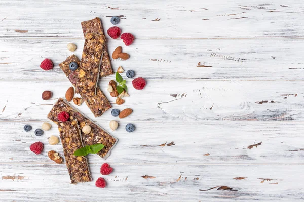 Taze ahududu, yaban mersini ve kopya alanı ile beyaz ahşap arka plan üzerinde sağlıklı beslenme için fındık karışımı ile granola enerji bar üst görünümü