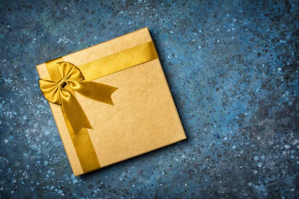 Zlatá dárková krabice s lesklým saténovým lukem — Stock fotografie
