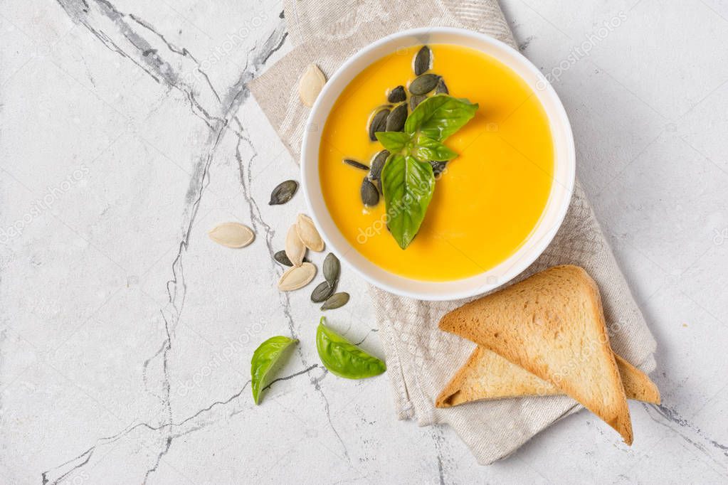 Bowl of vegetarian pumpkin soup with seeds and toast