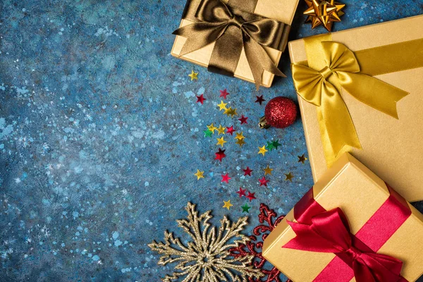Goldene Geschenkboxen mit glänzenden Satinschleifen mit Weihnachtsdekoration — Stockfoto