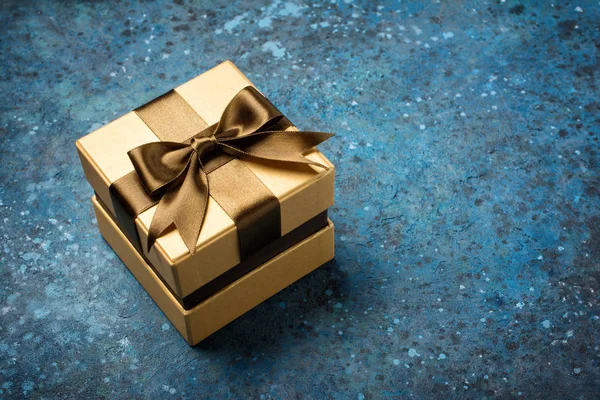 Golden gift box with shiny brown satin bow