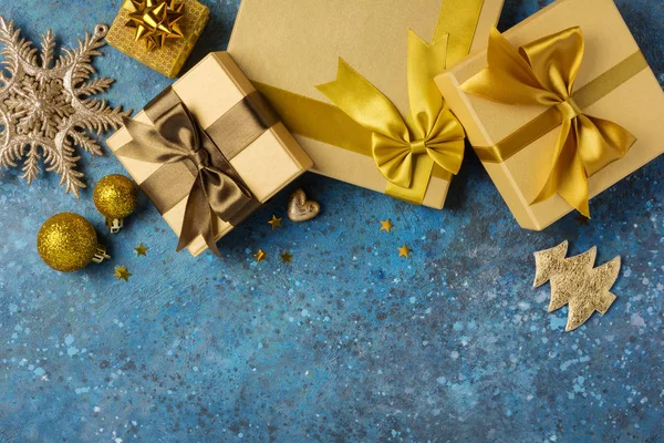 Zlaté dárkové krabice s lesklou hnědou saténovou mašlí a vánoční ozdobou — Stock fotografie