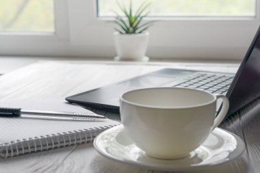 Açık pencere arkaplanına yazmak için siyah dizüstü bilgisayar, kalem ve defterle evde öğrenim için modern iş yeri