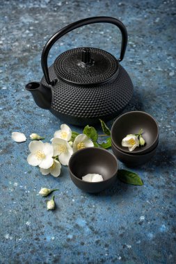 Asya 'nın geleneksel çaydanlığını ve mavi beton arka planda yeşil yasemin çayı bardaklarını kapatın.