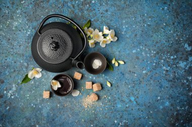 Asya 'nın geleneksel çaydanlığının en üst görüntüsü ve mavi beton arka planda ve kopyalama alanı ile sağlıklı yeşil yasemin çayı veya kahverengi şeker ile bardaklar