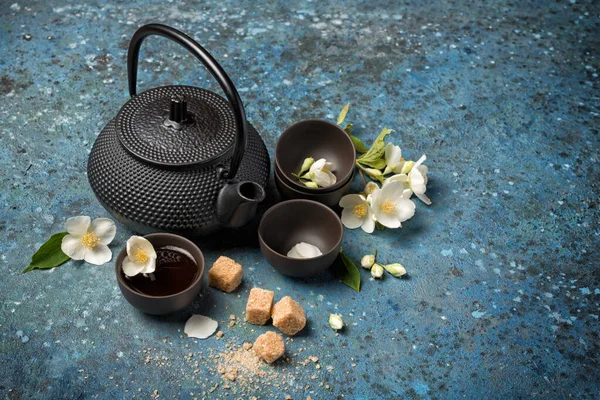 将亚洲传统的黑水壶和茶杯与健康的绿茉莉花茶 甘蔗或红糖在蓝色混凝土背景和复制空间紧密相连 — 图库照片