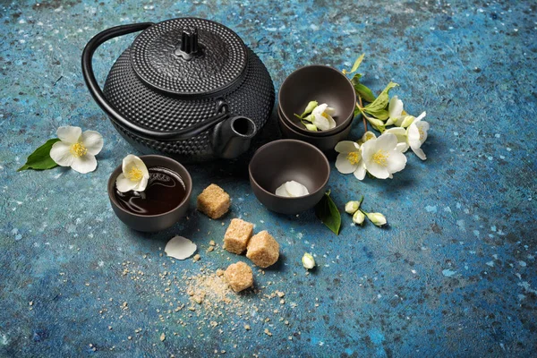 东方黑色传统水壶和杯子 配以健康的绿色茉莉花茶 带有甘蔗或红糖 蓝色混凝土背景 有复制空间 — 图库照片