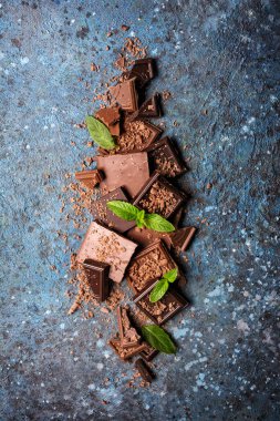 Kırık sütün ve mavi beton arka planda taze yeşil naneli siyah çikolatanın üst görüntüsü.