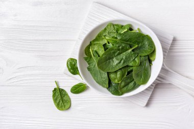 Tahta tahtada yeşil bebek ıspanağı ve fotokopi alanı olan beyaz ahşap zemin.