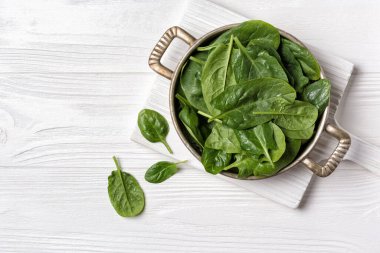 Yeşil taze ıspanak ve makasla ahşap tahtada ve beyaz ahşap arka planda eski tip fırın tabaklarının üst görüntüsü.