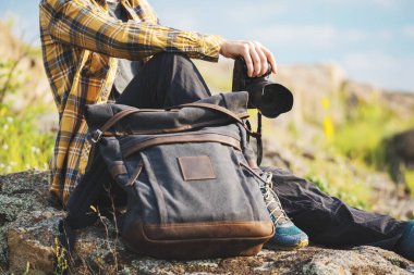 Koyu gri sırt çantalı genç yetişkin, manzara fotoğrafçılığı için kamera tutuyor. Seyahat kavramı