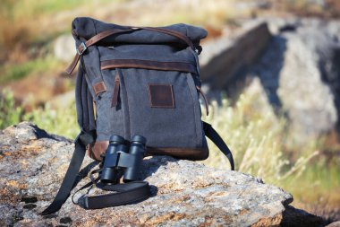 Koyu gri sırt çantalı kuş gözlemcisi ve etrafı kolaçan eden ve kuşları izleyen dürbünler.