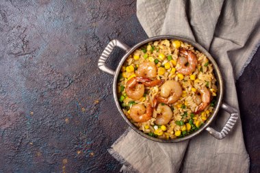 Çin pilavlı tava, lezzetli karidesler, sarı mısır, tavuk yumurtası ve yeşil soğanlı gri keten kumaş örtüsü ve fotokopi alanı olan koyu beton arka plan.