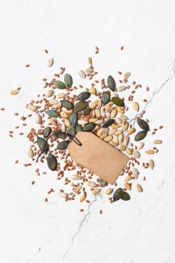 Beyaz mermer zemin üzerinde sağlıklı beslenme için balkabağı, ayçiçeği ve keten tohumlarının üst görünümü