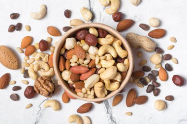 Badem, fındık, ceviz, fıstık, fındık ve çam fıstığı beyaz mermer arka planda.