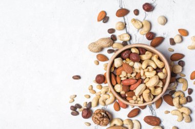 Badem, fındık, ceviz, fıstık, fındık ve çam fıstığı içeren beyaz mermer arka planda fotokopi alanı.