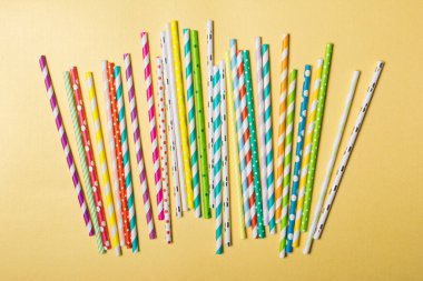 Parlak çizgili yeşil, sarı, pembe ve mor kokteyl pipetlerinin üst görünümü altın kağıt arka planda parti nitelikleri olarak