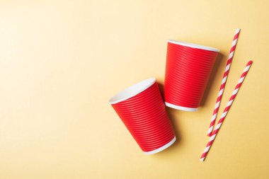 Altın kağıt zemin üzerinde çizgili kokteyl pipetleri ve fotokopi spac ile parlak kırmızı kullan-at servis bardağının üst görüntüsü