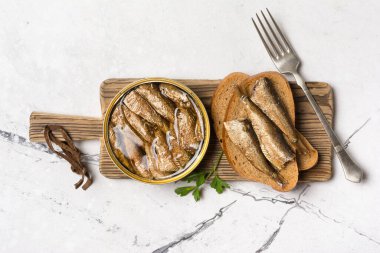 Yağ içinde balık, maydanozlu sandviç ve beyaz mermer arka planda çavdar ekmeği.