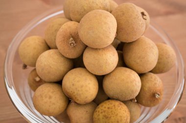 Dimocarpus Longan meyve üzerinde ahşap arka plan izole bir yığın ile dolu kase