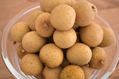 Dimocarpus Longan meyve üzerinde ahşap arka plan izole bir yığın ile dolu kase