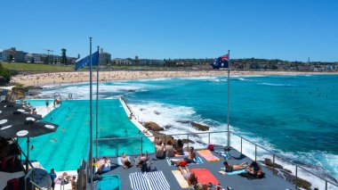 24 Aralık 2018, Bondi Sydney Avustralya: Yüzme havuzu ve Avustralya bayrağı önünde Bondi plaj panoraması insanlar Sydney Avustralya'da güneşli bir yaz gününde güneşleniyor