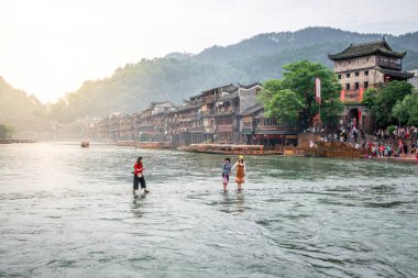 Çinli turistler earl taş köprü ve eski evler atlama üzerinde