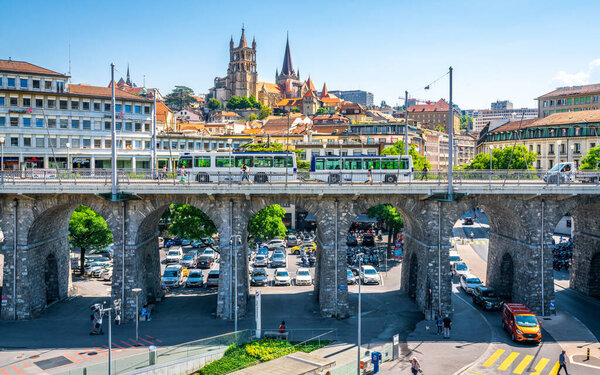 Lausanne Switzerland , 25 June 2020 : Cityscape of Lausanne city and view of the Grand-Pont or great bridge with a trolleybus on it and old Notre-Dame de Lausanne cathedral in background in Switzerland