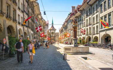 Bern İsviçre, 27 Haziran 2020: Simsonbrunnen veya Samson Fountain ve Zytglogge saat kulesiyle eski Kramgasse caddesinde turistler