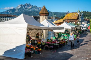 Lucerne İsviçre, 30 Haziran 2020: Lucerne sabah pazarı, Chapel köprüsü ve Pilatus arkaplanda 2020 yazında Lucerne İsviçre 'de bulunan insanlar ve tezgahlar