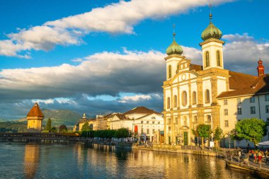 Lucerne İsviçre, 29 Haziran 2020: Lucerne Cizvit Kilisesi 'nin günbatımı, turistler Chapel Köprüsü ve Rigi Dağı ile birlikte 2020 yazında Lucerne İsviçre' de kurulmuştur.