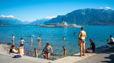 Vevey İsviçre, 4 Temmuz 2020: Vevey plajından Cenevre Gölü 'ne yüzen insanlar ve güneşli bir yaz günü Vevey İsviçre' de güzel sularda yelken açan turistik vapur
