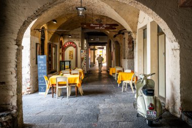 Morcote İsviçre, 1 Temmuz 2020: İsviçre 'nin İtalyanca konuşan Ticino bölgesinde kemerli galeri sokağının manzaralı pizzacı girişi ve Piaggio scooter' ı