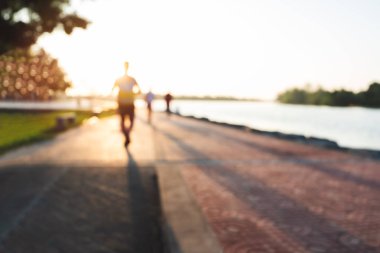 Runner bulanık grup akşam günbatımında parkta yayınlanıyor. İnsanlar yürürken, insanlar ve egzersiz. Fitness ve sağlıklı faaliyet yaşam tarzı.