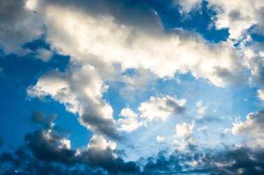 Mavi gökyüzü ve beyaz akşam günbatımında bulutlu.