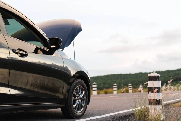 Yeni siyah araba Park asfalt yolda yan görünüm akşam günbatımında başlık açıldı. Kırsal Road mil taş ve doğa arka plan ile yaz aylarında otopark siyah Araba arızası.