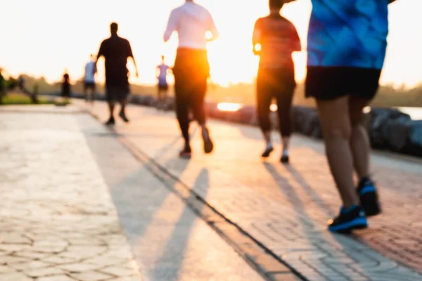 Runner bulanık grup akşam günbatımında parkta yayınlanıyor. İnsanlar yürürken, insanlar ve egzersiz. Fitness ve sağlıklı faaliyet yaşam tarzı.