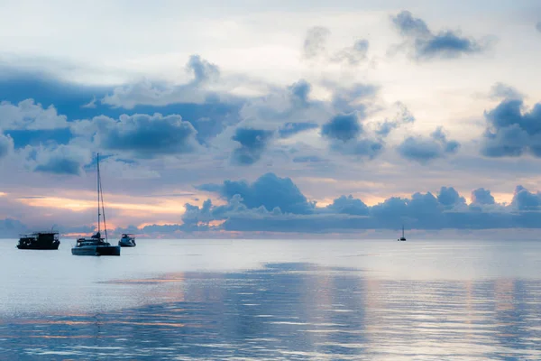 Soft focus of boats in the middle of sea suface amidst dark clouds at sunset.
