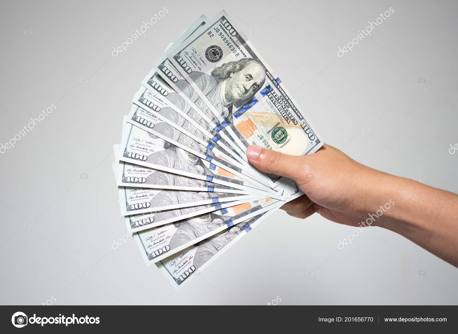 美元的钞票在白色的背景手关闭商人手中持有或给100美元钞票的财政或捐赠概念—— 库存社论照片© cherayut000 #201656770