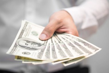 Para el üstünde tutan, yüz bizi dolar faturaları finansal kavramlar, seçici odak içinde yayılan iş adamı.