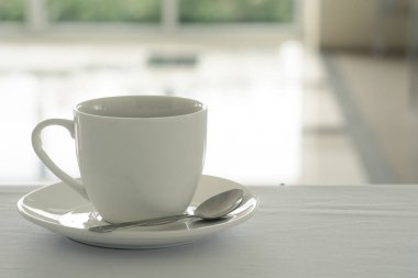 Kahve fincan beyaz masanın üzerine yerleştirilen ve taze sabah kahve dükkanında Bahçe arka plan bulanık.