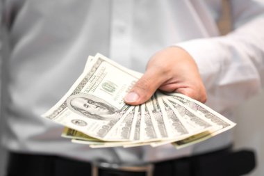 Para el üstünde tutan, yüz bizi dolar faturaları finansal kavramlar, seçici odak içinde yayılan iş adamı.