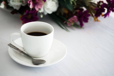 Siyah kahve kafede beyaz masa ve çiçek arka plan üzerine yerleştirilen.