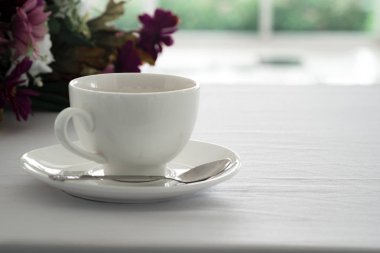 Sabah beyaz masa çiçek ve kahve dükkanında bulanık Bahçe arka plan siyah kahve yerleştirilen.