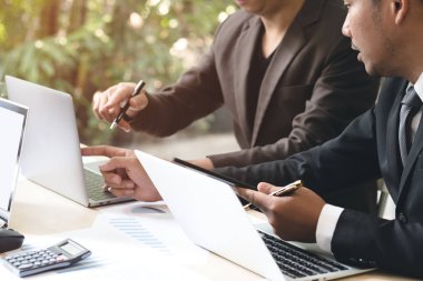 Ofiste toplantı sırasında dizüstü ve touch kullanarak iki genç işadamları yastık. Girişimciler el sırasında tartışma ve tasarım fikir ekranında işaret ve çalışma alanı'ndaki ahşap masa üzerinde planlama.