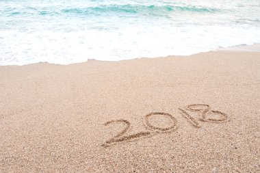 Mutlu yeni yıl 2018 kavramı. Sayı 2018 kumsalda mavi deniz dalgaları ve köpük ile yazılmış. Tropikal yaz plaj tatil, tatil ve yeni yıl kutlamaları.