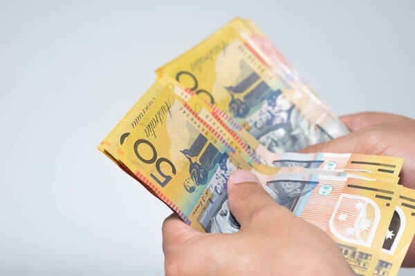 Businessman hands counting fifty Australian Dollar bills isolated on gray background. Hand holding or giving Australian money banknotes in concept of currency exchange and payment.