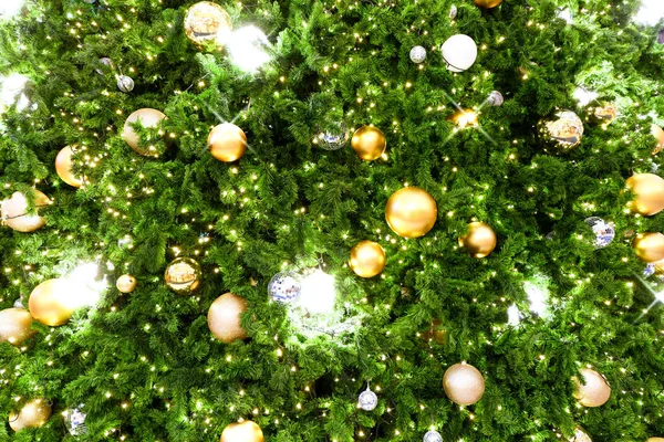 Noel ağacı süslenmiş Noel altınları ve gümüş toplar ağaçta asılı. Bayram ve şenlik arka planında parıldayan ışıklar var..