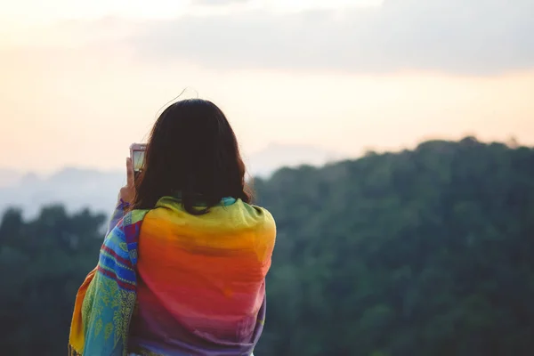 年轻女子旅行者在山上拍照与智能手机 时髦的女孩是拍摄美丽的山景观视频在手机相机 暑假旅游和度假 — 图库照片